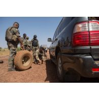 Des soldats aident leurs camarades nigériens à changer la route de leur pick-up sur la route de Niamey, au Niger.