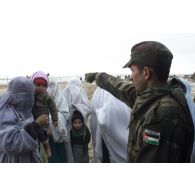 Consultations pour la population civile à l'hôpital jordanien de l'aéroport de Mazar e Charif. Un soldat jordanien, assurant la sécurité à l'entrée de l'hôpital, gère l'affluence et la file d'attente des femmes afghanes voilées venues consulter.
