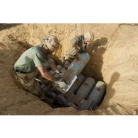 Un sapeur du 31e régiment du génie (31e RG) place des bombes d'aviation dans un fourneau creusé dans le sable pour leur destruction en vallée d'Inaïs, au Mali.