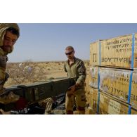 Un sapeur du 6e régiment du génie (6e RG) aidé d'un soldat malien exhume des caisses de munitions enfouies dans le sable en vallée d'Inaïs, au Mali.