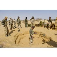 Un sapeur du 31e régiment du génie (31e RG) inspecte le périmètre d'une cache d'armes enfouie dans le sable en vallée d'Inaïs, au Mali.