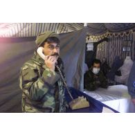 Consultations pour la population civile à l'hôpital jordanien de l'aéroport de Mazar e Charif. Un militaire jordanien téléphone, à proximité de femmes afghanes voilées assises dans la salle d'attente des admissions venues consulter.