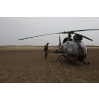 Un pilote du 5e régiment d'hélicoptères de combat (5e RHC) ravitaille son hélicoptère Gazelle HOT SA-342 en carburant à Goundam, au Mali.