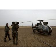 Des pilotes d'hélicoptère Gazelle SA-342 du 5e régiment d'hélicoptères de combat (5e RHC) arment un missile HOT sur leur appareil en recomplètement de carburant à Goundam, au Mali.