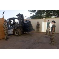 Des soldats de la 7e antenne chirurgicale parachutiste (7e ACP) récupèrent du matériel au moyen d'un chariot Valmet sous l'objectif d'un caméraman sur l'aéroport de Bamako, au Mali.