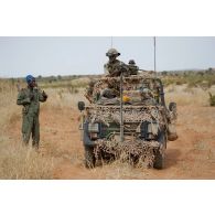 Des légionnaires du 1er régiment étranger de cavalerie (1er REC) montés à bord d'un véhicule léger tout terrain (VLTT) Peugeot P4 croisent un soldat malien lors d'une patrouille à Mopti, au Mali.