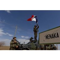 Un soldat du 1er régiment de hussards parachutistes (1er RHP) accroche le drapeau français à la hampe de son véhicule blindé léger (VBL) avant d'entrer dans la ville de Ménaka, au Mali.