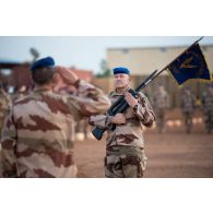 Le porte-drapeau du 5e régiment d'hélicoptères de combat (RHC) présente les armes à l'officier adjoint du groupement tactique désert Homobri à Gao, au Mali.
