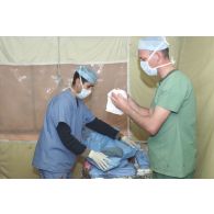 Au bloc opératoire de l'hôpital jordanien de Mazar e Charif, intervention chirurgicale orthopédique franco-jordanienne sur la jambe d'un patient afghan. Préparation du personnel avant l'intervention.