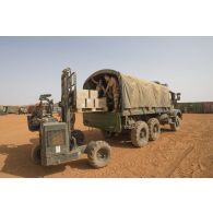 Des soldats du régiment de soutien du combattant (RSC) chargent des cartons de bouteilles d'eau à bord d'un camion GBC-180 en zone logistique de Gao, au Mali.