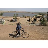 Portrait d'un enfant à vélo dans les faubourgs de Markala sur les berges du fleuve Niger, au Mali.