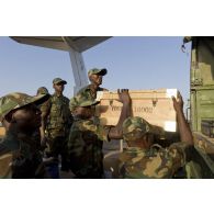 Des soldats togolais chargent du matériel à l'arrière d'un camion GBC-180 sur l'aéroport de Bamako, au Mali.