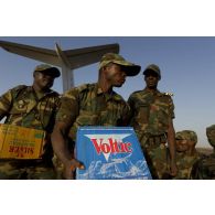 Des soldats togolais chargent des cartons de bouteilles d'eau et de la nourriture sur l'aéroport de Bamako, au Mali.