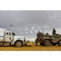 L'équipage d'un véhicule de l'avant blindé (VAB) dépanne un camion semi-remorque ensablé sur la route de l'aéroport de Goundam, au Mali.
