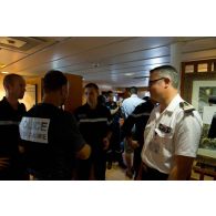 Un officier de police judiciaire discute avec l'équipage de la frégate de surveillance Ventôse aux côtés du capitaine de frégate Jean-Emmanuel Perrin à Fort-de-France, en Martinique.