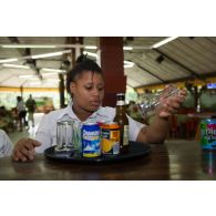 Une volontaire prépare les commandes des clients lors d'un cours pratique sur le service à table au restaurant pédagogique du régiment du service militaire adapté (RSMA) à Saint-Jean-du-Maroni, en Guyane française.