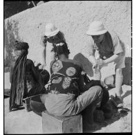 Des officiers des troupes coloniales regardent des femmes qui préparent de l'huile d'arachide.