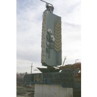 Sculpture portrant des inscriptions en cyrillique et en arabe à l'entrée d'une usine à Mazar e Charif, surmontée d'un portrait du commandant Massoud.