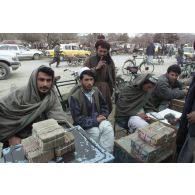 Marchands pratiquant le change au marché de l'argent du centre-ville de Mazar e Charif, veillant sur des paquets de liasses de billets en afghani, la monnaie locale.
