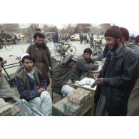 Marchands pratiquant le change au marché de l'argent du centre-ville de Mazar e Charif, veillant sur des paquets de liasses de billets en afghani, la monnaie locale. Transaction avec un client.