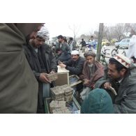 Marchands pratiquant le change au marché de l'argent du centre-ville de Mazar e Charif, veillant sur des paquets de liasses de billets en afghani, la monnaie locale. Transaction avec un client.