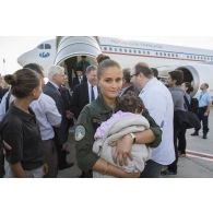 Un personnel navigant porte un bébé irakien à son arrivée sur l'aéroport de Roissy-Charles-de-Gaulle.