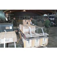 Préparatifs au départ en Afghanistan pour le 21e RIMa (régiment d'infanterie de marine). Confection de palettes de matériel dans un hangar à Istres : une caisse de pains de plastic au premier plan.