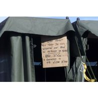 Installations sanitaires de campagne au camp français de l'aéroport de Mazar e Charif. Commentaires peu amènes sur le manque d'hygiène de certains inscrits sur un carton.