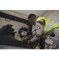 Un mécanicien effectue les derniers réglages sur la combinaison de vol d'un pilote de chasse avant de partir en mission depuis la base aérienne projetée (BAP) en Jordanie.
