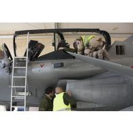 Un pilote de chasse et des mécaniciens effectuent la visite pré-vol d'un avion Rafale sur la base aérienne projetée (BAP) en Jordanie.