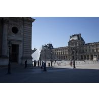 Des civils déambulent au sein de la cour Napoléon du Palais du Louvre à Paris, lors du premier jour du déconfinement.