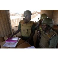 Des soldats maliens se mettent en liaison avec un avion pour informer le pilote sur la direction de la cible à atteindre lors d'une formation au guidage aérien tactique avancé (GATA) à Gao, au Mali.