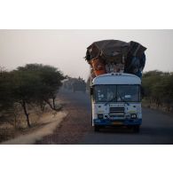 Un autobus civil croise la route d'un convoi du 16e bataillon de chasseurs à pied (16e BCP) sur une route de la région de Niamey, au Niger.