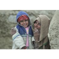Camp de réfugiés afghans à Mazar e Charif. Portrait d'une enfant dans les bras d'une femme.