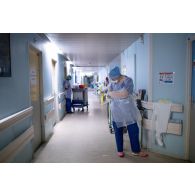 Une étudiante infirmière de l'EPPA enfile une blouse dans un couloir du service pneumologie de l'HIA de Percy.