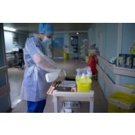 Une étudiante infirmière de l'EPPA désinfecte un plateau-repas dans un couloir du service pneumologie de l'HIA de Percy.