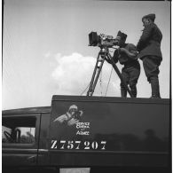 Un opérateur de prise de vue du SCA et son aide sont photographiés sur le toit du camion SCA immatriculé Z757207 en contre-plongée lors d'un tournage  au fort du Télegraphe, sous le col du Galibier.