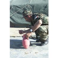 Un soldat jordanien, portant un brassard du Croissant-Rouge, symbole des services de santé, se lave les mains au pied d'une tente.