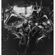 Sous-marinier et officier marinier dans le compartiment des moteurs Diesel de la salle des machines du sous-marin des Forces navales françaises libres (FNFL) la Minerve, au cours d'un exercice.