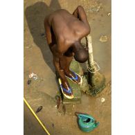 Un homme se lave dans des condition sommaires à un point d'eau dans le quartier de Sebroko (commune d'Attécoubé).
