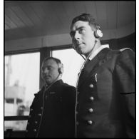 Portrait du lieutenant de vaisseau, commandant le patrouilleur La Lorientaise en compagnie d'un officier marinier, écouteurs sur les oreilles, à la passerelle de commandement.