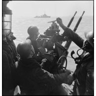 Des canonniers mettent en oeuvre une mitrailleuse double Hotchkiss de 13,2 mm de défense antiaérienne à bord d'un torpilleur léger.