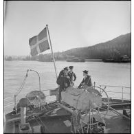 Des marins britanniques et français discutent sous le pavillon hissé sur un cargo danois saisi par la Royal Navy et remis à la Marine nationale.