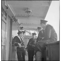Des marins britanniques et français discutent sur le pont d'un navire marchand saisi par la Royal Navy et remis à la Marine nationale.
