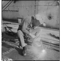 Un ouvrier assemble des pièces de blindage au chalumeau à bord du croiseur Richelieu en construction à l'arsenal de Brest.
