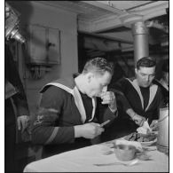 Des marins mangent des huîtres au cours du réveillon de Noël à bord du porte-avions Béarn.