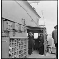 Capitaine de frégate aux jumelles près d'une boîte à pavillons sur la passerelle inférieure à bord du contre-torpilleur Guépard.