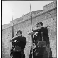 Deux sentinelles d'une unité de défense côtière, canonniers marins algériens, dits Baharia, sont en faction au fort de Mers-el-Kébir et  présentent les armes.