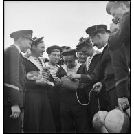Des membres d'équipage du contre-torpilleur Le Malin examinent une bouée endommagée par une munition de mitrailleuse d'avion.
