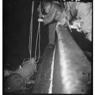 Au cours d'une mission de dragage de nuit, des marins mettent à l'eau le cochonnet de drague depuis un chalutier réquisitionné par la Marine nationale.